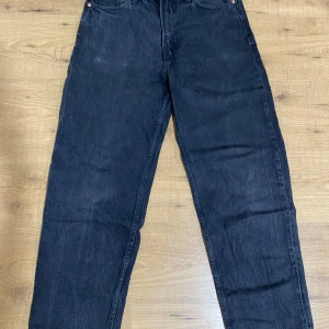 Svarta loose fit jeans från H&M - Svarta jeans från H&M i loose fit-modell med raka ben och klassisk femficksdesign. Jeansen är tillverkade i bomull och har en avslappnad passform som ger en chill vibe. Perfekta för dig som gillar en lite baggy stil.
