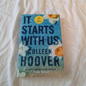 It Starts With Us - En gripande roman av Colleen Hoover, perfekt för dig som gillar starka känslor och relationer. Boken har en snygg omslagsdesign med blommor och vatten, och är skriven av författaren till succén 'It Ends With Us'.