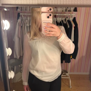 Vit blus med spetsdetaljer - Säljer en söt vit blus med transparenta långärmar och fina spetsdetaljer upptill. Från Hm, vet ej storlek men skulle gissa på M/S🤩