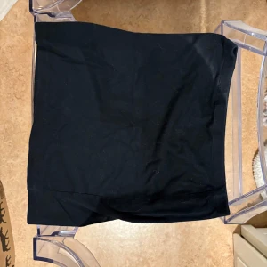 Svart kortkjol från Calliope - Enkel och stilren svart kortkjol från Calliope. Kjolen har en rak passform och är tillverkad i ett mjukt och stretchigt material som sitter bekvämt på kroppen. Perfekt att matcha med en crop top eller oversized hoodie.