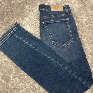 Blå Replay slimfit jeans  - Säljer ett par klassiska blå jeans från Replay med snygga kontrastsömmar och detaljer på fickorna. Jeansen har slimfit passform, tillverkade i slitstarkt denimtyg. Perfekta för dig som gillar en tidlös och stilren look.