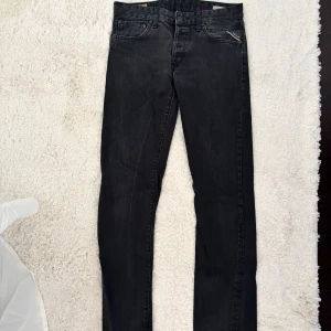 Svarta Replay jeans straight fit - Säljer ett par svarta Replay jeans i slim fit med klassisk femficksdesign och snygga detaljer. Jeansen har en mörk tvätt. Storlek W32 L34. Midjemåttet är ca 41 cm rakt över och innerbenslängden är ca 82 cm.