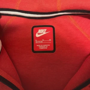 Röd Nike hoodie med dragkedja S - Nike hoodie i rött med svart logga på bröstet och hel dragkedja framtill. Tröjan har huva, långa ärmar och två svarta fickor med dragkedja. Perfekt för dig som gillar sportig och stilren look.