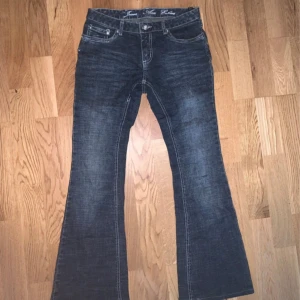 Mörkblå bootcut jeans från Jouer Aux Echecs - Snygga mörkblå bootcut jeans från Jouer Aux Echecs med broderade bakfickor och klassisk femficksdesign. Jeansen har markerade sömmar och en lätt tvättad look. Perfekta för dig som gillar en retro vibe och vill sticka ut lite extra.