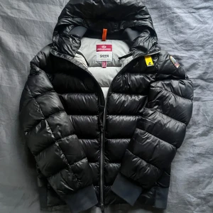 Parajumpers Sheen dunjacka  - Säljer den sjukt eftertraktade svarta dunjackan från Parajumpers, modell Sheen. Jackan har en glansig finish, huva, dragkedja framtill och den klassiska gula detaljen vid halsen. Riktigt snygg nu till vintern! Om du har några frågor är det bara att skriva! 🍁🍁