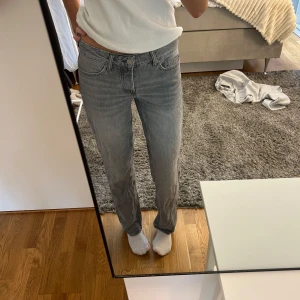 Grå raka jeans i klassisk modell - Säljer ett par grå jeans med rak passform och klassisk femficksdesign. Jeansen har normal midja och är tillverkade i mjukt denimtyg. Perfekta för dig som gillar en enkel och stilren look.