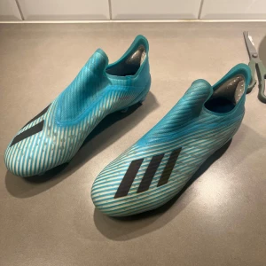 Blåvita adidas fotbollsskor utan snörning - Säljer ett par blåvita adidas fotbollsskor, är i användt skick men är fortfarande i bra skick