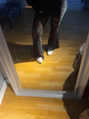 Sv charmade spetsbyxor med utsvängda ben - Säljer ett par svarta, transparenta spetsbyxor med blommigt mönster. Byxorna har utsvängda ben och sitter tajt upptill för en snygg siluett. Perfekta om du vill sticka ut och addera lite edge till din outfit.