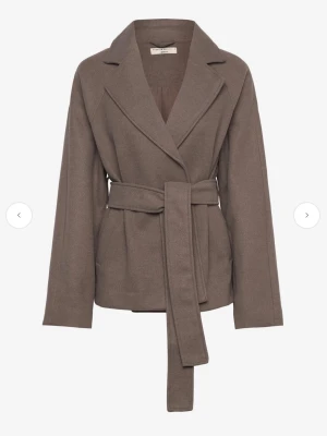 Brun kappa med bälte från Gina tricot - Snygg brun kappa från Gina tricot. I bra skick använd ett fåtal gånger