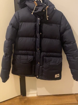 Mörkblå dunjacka från The North Face - Säljer en mörkblå dunjacka från The North Face. Den är perfekt till att åka skidor eller bara att ha den som en vanlig jacka. Tyvärr har den lite smink fläckar men inget man ser.❤️