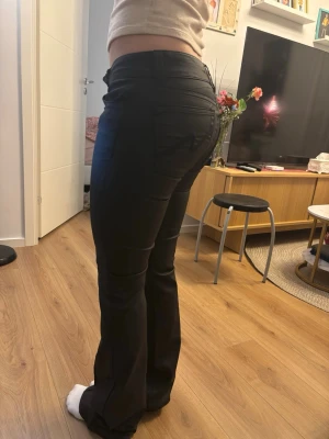 Svarta bootcut skin jeans från Nelly - Säljer ett par svarta skin jeans från Nelly med bootcut passform och snygga broderade detaljer på bakfickorna. Jeansen har låg midja och är gjorda i ett stretchigt bomullsmaterial som sitter riktigt snyggt. Perfekta till sneakers eller boots. Storlek 34, själv har jag storlek 36 så de sitter för tajt, på mig är de långa i längden då jag är 164cm och byxorna har aldrig används. 