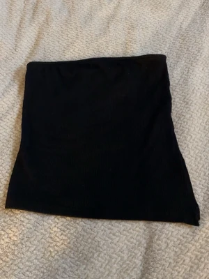 Svart bandeau tubtopp från Pieces - Säljer en svart bandeau tubtopp från Pieces i storlek M. Toppen är ribbad och helt ärmlös, perfekt för sommardagar eller som layering-piece. Toppen har en slits på ena sidan. Enkel och stilren design som är lätt att matcha med olika outfits.