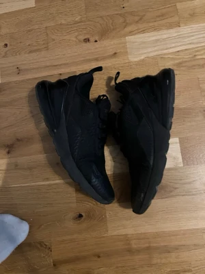 Svarta Nike Air Max 270 sneakers strl 44 - Nike Air Max 270 sneakers i helsvart färg med mesh-överdel och synlig Air-enhet i hälen. Skorna har snörning, rund tå och platt sula. Snygg och sportig design med diskreta Nike-loggor på sidan och tungan. Perfekt för dig som gillar streetwear och sportig stil. Liten defekt, men syns knappast, skorna hade precis blivit tvättade då bilderna blev tagna så de kan uppfattas som blöta, strl 44, skriv vid frågor och funderingar 