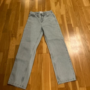 Ljusblå raka jeans från grunt - Säljer ett par ljusblå jeans från grunt med klassisk femficksdesign och raka ben. Jeansen har hög midja och är tillverkade i slitstarkt denim. Passar dig som gillar en chill och tidlös look. Dragkedja och knapp framtill, samt grunt-lapp bak på midjan. Anvönda två gånger liten fläck men man märker kanptt det