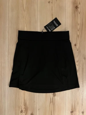 J.Lindeberg TX Jersey kjol - S - Snygg  svart kjol från J.Lindeberg i TX Jersey-material med 4-vägsstretch, snabbtorkande och fukttransporterande egenskaper. Bred midja och diskret JL-logga bak. Perfekta för dig som vill ha sportig stil och maximal rörelsefrihet.