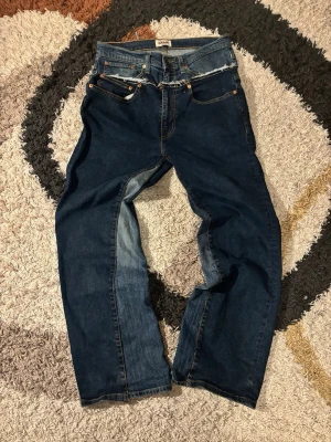 Mörkblåa jeans - omsydda - Mörkblå jeans i storlek 34/32, omsydda från två par jeans till ett. Lagt några timmar på att göra om. Väldigt nya, inga av originaljeansen var använda. Vid fler frågor hör av er!!! 