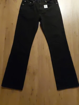 Oanvända jeans från lager 157 - Svarta jeans från lager 157 med klassisk femficksdesign och bootcut-ben. Jeansen har normal passform och är tillverkade i ett slitstarkt bomullsmaterial. Perfekt för dig som gillar en tidlös och enkel stil. Storlek W29 L32.   Nypris 400 kr 