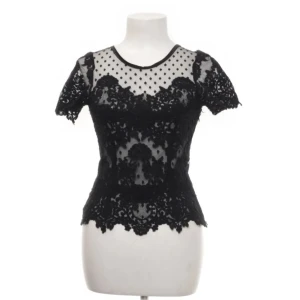 Svart spets topp från Ida Sjöstedt  - Svart spetstopp med korta ärmar och ett vackert mönster från Ida Sjöstedt, finns inte kvar på hemsidan ✨Toppen har en dragkedja på ena sidan. Materialet är inte så töjbart så skulle säga den lutar mer mot XS än S :) Skickar samma dag/dagen efter💞