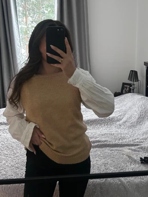 Beige stickad väst S M  - Säljer en beige stickad väst i mjukt material. Västen har breda axelband, rund halsringning och ribbade kanter. Perfekt att styla över en skjorta eller långärmad topp för en trendig lager-på-lager-look.