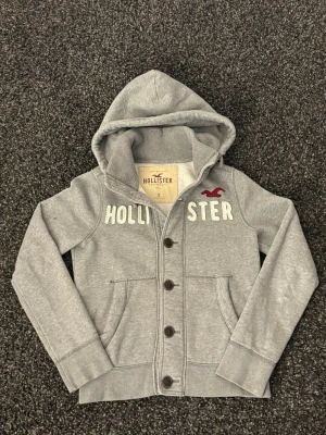 Hollister cardigan-sällsynt - Säljer nu denna sjukt eftertraktade Hollister cardigan. Mycket fin hoodie i skick 8/10. Väldigt populär modell och perfekt för säsongen. Obs väldigt bra skick bara lilla fläcken på bilden!  • Perfekt till kyligare dagar • Skön passform, lätt att styla • Vintage / Y2K-inspirerad – sällsynt och eftertraktad • Passar både vardag och layering  📏 Storlek: S 📦 Skickas omgående 💬 Pris kan diskuteras vid snabb och smidig affär 