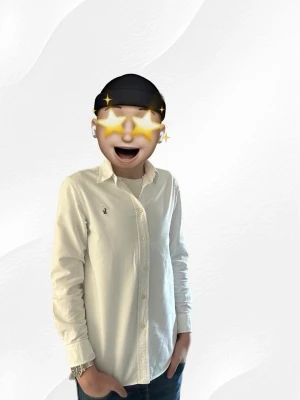 Vit skjorta från Ralph Lauren - Klassisk vit skjorta från Ralph Lauren med broderad logga på bröstet. Skjortan har normal passform, långa ärmar och knäppning framtill. Tillverkad i bomull och passar perfekt till jeans eller chinos. Storlek 16a modellen är 170 cm lång. 