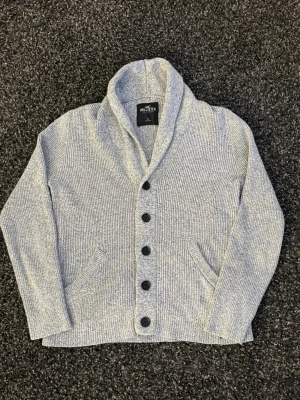 Grå stickad kofta från Hollister - Säljer nu denna sjukt eftertraktade Hollister kofta. Mycket fin hoodie i skick 9/10. Väldigt populär modell och perfekt för säsongen.  • Perfekt till kyligare dagar • Skön passform, lätt att styla • Vintage / Y2K-inspirerad – sällsynt och eftertraktad • Passar både vardag och layering  📏 Storlek: S 📦 Skickas omgående 💬 Pris kan diskuteras vid snabb och smidig affär 