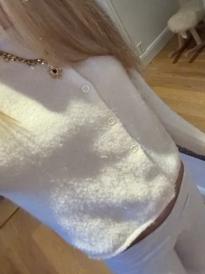 Mysig vit kofta i ullmix - Supermjuk och fluffig vit kofta med lång ärm och knappar framtill. Tröjan har en klassisk, enkel design och är lite croppad i modellen. Perfekt för lager på lager och att mysa i under kyliga dagar.