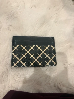 By Malene Birger kortplånbok - Snygg kortplånbok i svart och beige med ett grafiskt rutigt mönster från Malene Birger. Plånboken har flera fack för kort och är tillverkad i skinn med en stilren och kompakt design.