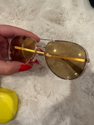 Guldiga aviator-solglasögon Michael Kors - Säljer ett par snygga aviator-solglasögon från Michael Kors, modell Chelsea. Glasen är tonade i brunt och bågarna är i guldig metall. Klassisk pilotform.