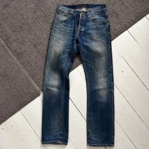 Mörkblåa Nudie Average Joe Jeans - Väldigt fina Nudie Jeans i Average Joe modell. | W29 L32. | Väldigt fint skick förutom att modell-lappen är lite sliten (ingenting alls man tänker på). | Längd: 108cm, Midja: 37-41cm (Stretch). | Tydliga honeycombs & whisker fades. | Skriv vid minsta fundering, pris ej hugget i sten!