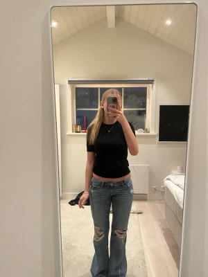 Svart stickad topp från Zara - En svart stickad topp från Zara med korta ärmar och rund hals. Toppen har snygga guldfärgade knappar bak i nacken som detalj. Inga defekter. Hör av er för fler frågor💗