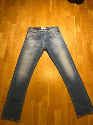 Replay Grover Hyperflex ljusblå jeans - Säljer ett par Replay Grover Hyperflex jeans i ljusblå tvätt med snyggt slitna detaljer. Modellen är straight fit med klassiska fem fickor och läderpatch bak i midjan. Jeansen är tillverkade i stretchigt denim för extra komfort och har Replay-logga på myntfickan.