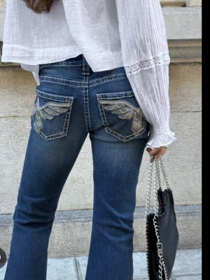 Blå bootcut jeans från Gina Tricot XS - Snygga blå bootcut jeans från Gina Tricot i storlek XS. Jeansen har broderade glitter detaljer på bakfickorna och klassiska femficksdesignen. De är i jeansmaterial och har en mycket lågmidjad passform som ger en modern vibe.