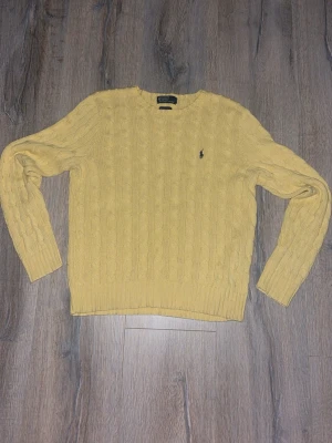 stickad tröja från Polo Ralph Lauren - Snygg gul kabelstickad tröja från Polo Ralph Lauren i 100% pima bomull. Tröjan har rund hals, lång ärm och klassisk broderad logga på bröstet. Perfekt för dig som gillar stilrena och tidlösa plagg med lite färg. Kontakta mig vid frågor.😁Storlek L