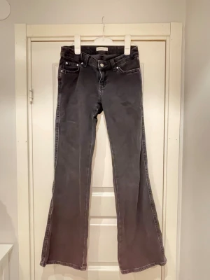 Svarta bootcut jeans med fickor bak - Snygga svarta jeans med bootcut-modell och coola fickor med lock och knapp bak.