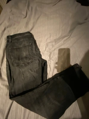 Svarta tapered jeans Jack & Jones w32 l32 - Säljer ett par svarta jeans från Jack & Jones, modell Tapered Mike i storlek 32. Jeansen har slitna detaljer och klassisk femficksdesign. Materialet är jeans med en mörk tvätt och smalare ben nedtill för en modern look.