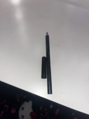 W7 King Kohl svart kajalpenna - Säljer en svart kajalpenna från W7, modell King Kohl. Pennan har klassisk träform med svart plasthylsa och lock. Perfekt för att skapa intensiva och definierade ögonlooks. Enkel att vässa och smidig att använda för både skarpa och suddade linjer.