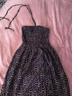 Leopardmönstrad kort klänning - Säljer en snygg kort klänning med leopardmönster i svart och lila. Klänningen har band så att man kan knyta runt nacken! Rätt så somrigt 😋