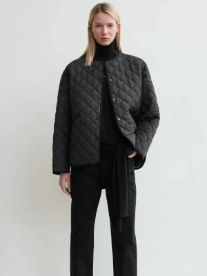 Svart quiltad jacka från Totême - Quiltad svart jacka från Totême med oversized passform och rund halsringning. Jackan har tryckknappar framtill, två snedställda fickor och ett stilrent rutmönster. Perfekt för lager-på-lager och enkel att styla till allt.