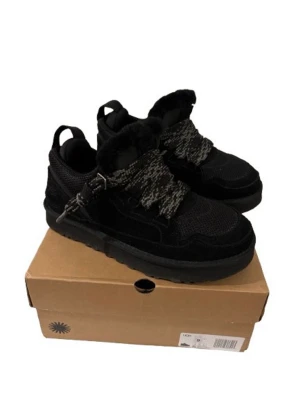 Svarta UGG sneakers med fuskpäls - Snygga svarta sneakers från UGG med grov sula, detaljer i mocka och mesh. Skorna har breda, mönstrade snören och en modern, chunky look. Perfekta för dig som vill ha både stil och komfort i vardagen. Riktigt bra nu till kyliga dagar 🥶Allt på bilderna tillkommer samt extra snören, hör av er om ni har frågor☺️