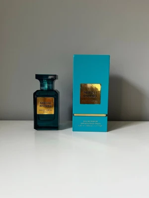 Neroli Riviera Eau de Parfum 80ml - Parfymflaska i elegant mörkt turkost glas med guldetikett och matchande turkos förpackning. Flaskan har en fyrkantig form och exklusiv känsla. Innehåller 80 ml Eau de Parfum. Perfekt för dig som gillar lyxiga och fräscha dofter.