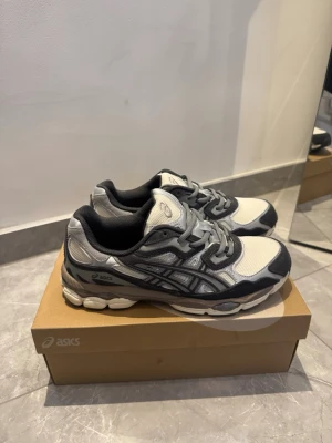 Asics GEL sneakers i beige/brun och vit - Snygga Asics GEL sneakers i beige/brun och vig med detaljer. Skorna har mesh- och syntetpaneler, klassisk snörning och en chunky sula för extra komfort. Perfekta för dig som gillar sportig stil och streetwear.