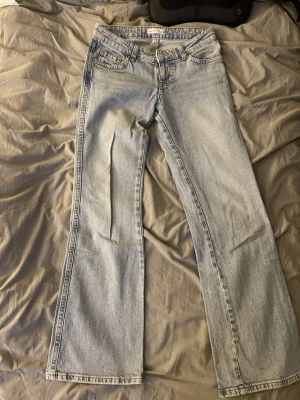 Ljusblå lågmidjade jeans - Säljer ett par ljusblå bootcut jeans från Gina tricot. Jeansen hag en extra ficka med lock och knapp bak. Pris går att diskutera ☺️