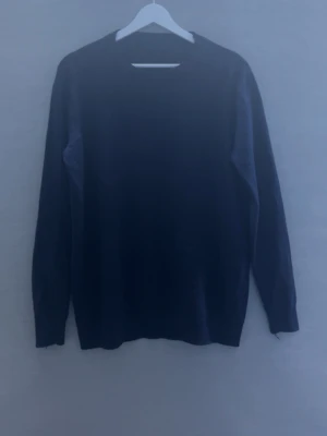 Marinblå stickad tröja - En enkel och stilren mörkblå stickad tröja med rund hals och långa ärmar. Tröjan har en klassisk passform och är gjord i mjukt stickat material som passar perfekt till lager på lager. Inga synliga detaljer eller mönster. Ingen lapp eller något som står vilken strl men passform är S-M och känns nästan som kashmir.