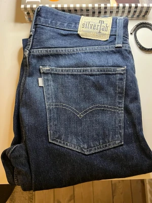 Levi's SilverTab mörkblå jeans - Mörkblå jeans från Levi's SilverTab med klassisk femficksdesign och raka ben. Jeansen har en tydlig SilverTab-patch bak i midjan och är gjorda i kraftig denim. Perfekta för dig som gillar en avslappnad och tidlös stil.
