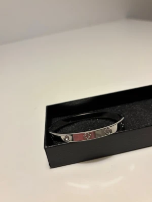 Cartier liknande armband  - Cartier liknande armband i silver med stenar i. Det ger en lyxig känsla och passar till alla tillfällen. Den är helt ny och oanvänd.