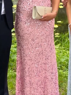 Rosa glittrig långklänning - Säljer en rosa långklänning med glittriga paljettdetaljer. Klänningen har figurnära passform och är ärmlös, perfekt för bal eller festligare tillfällen. . Supersnygg och elegant look och öppen rygg!