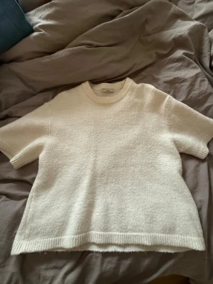 Vit stickad t-shirt från Arket - Populär stickad tröja från Gina, kan se nopprig ut på bilden men materialet är så på tröjan, den är använd bara några få gånger