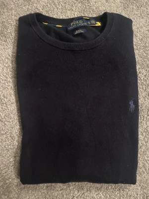 Mörkblå stickad tröja från Polo Ralph Lauren - Mörkblå stickad tröja från Polo Ralph Lauren. Säljer för att den är för liten. Nyskick inte blivit använd så mycket