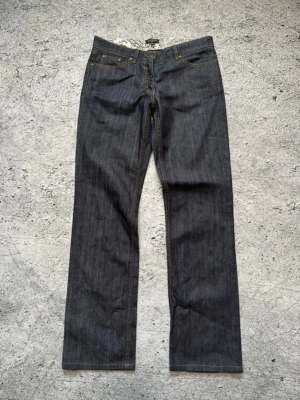 Mörkblå raka jeans från Paul Smith - Snygga mörkblå jeans från Paul Smith med rak passform och klassiska fem fickor. Jeansen har kontrastsömmar och är gjorda i ett robust denimtyg. Perfekta för dig som gillar stilrena och tidlösa plagg.